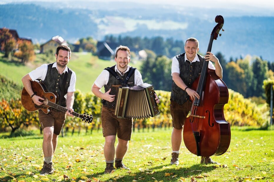 Die Pagger Buam mit Gitarre, Steirischer Harmonika und Kontrabass in der weststeirischen Landschaft