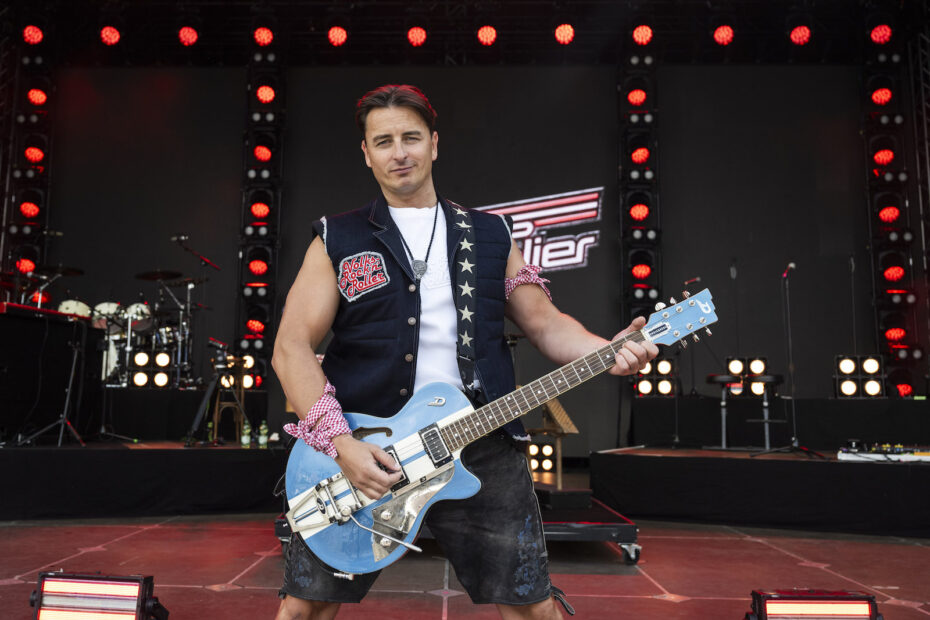 Andreas Gabalier mit hellblauer E-Gitarre auf einer beleuchteten Konzertbühne